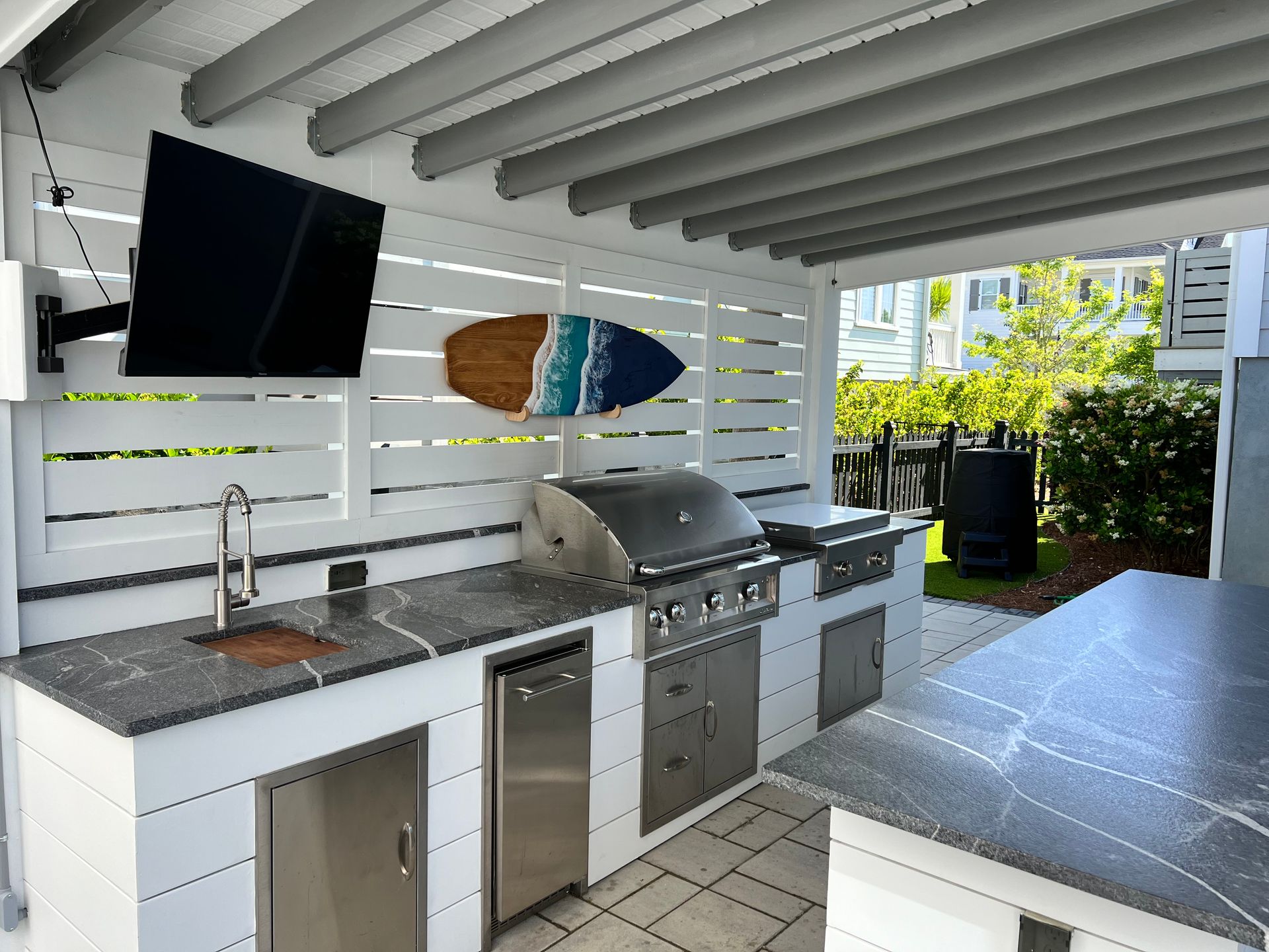 Outdoor kitchen with TV and slat-wall backdrop