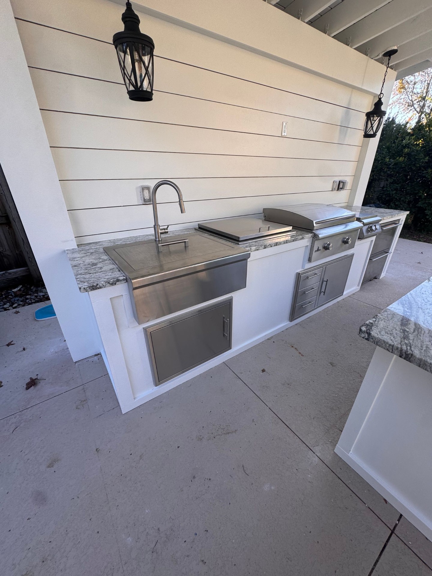 White outdoor kitchen with stainless sink and grill