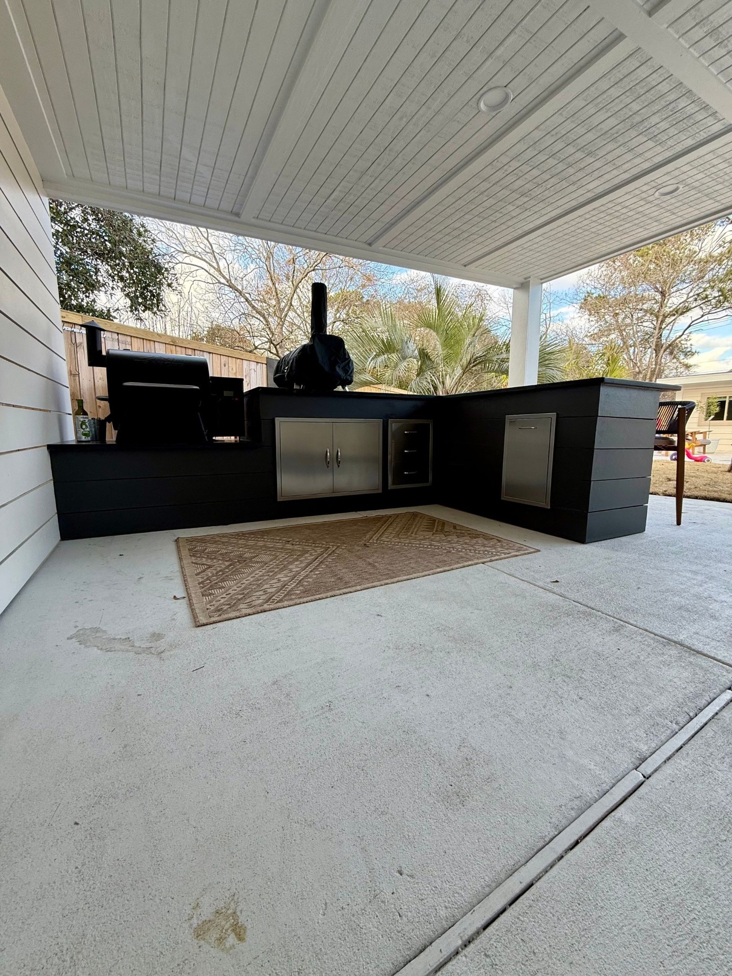 Wide view of a black outdoor kitchen under a covered patio