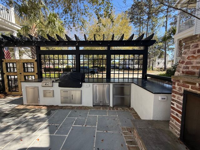 Black pergola over an outdoor kitchen and grill