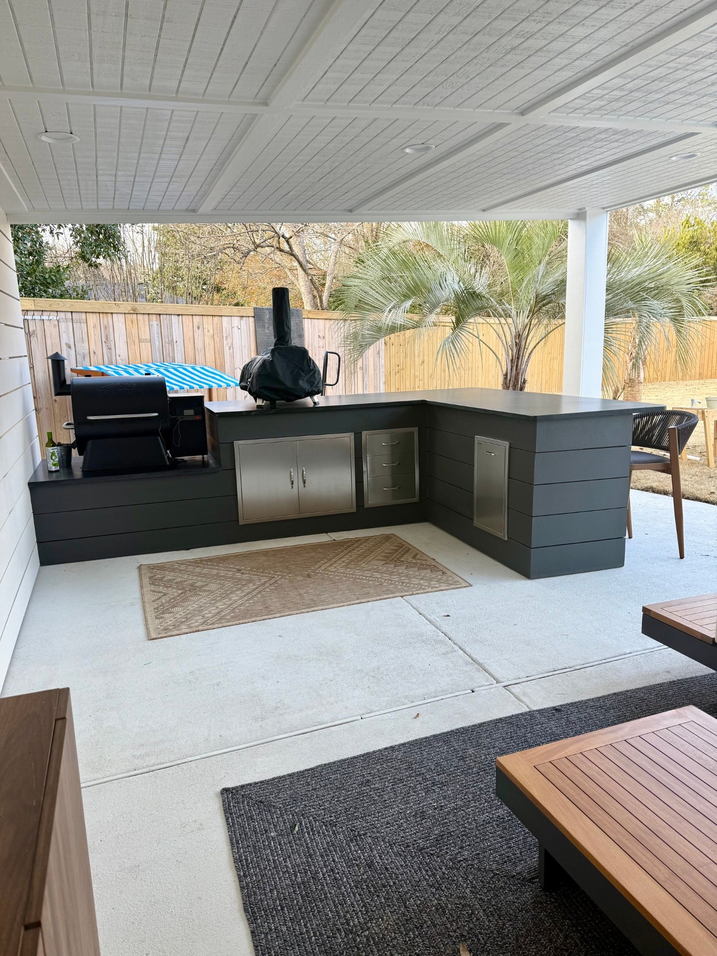 Dark outdoor kitchen with smoker and bar seating